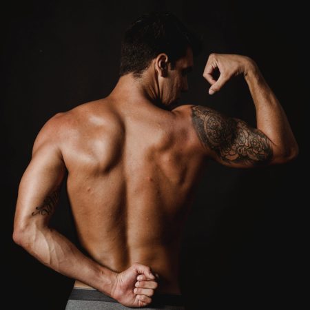 A muscular man seen from behind in grey underwear.